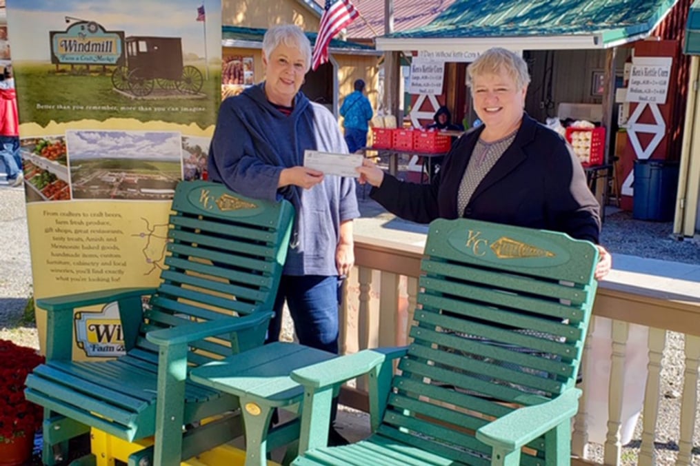 Mary Record, a longtime vendor at the Windmill and President of the organization's Board, presents a check from the Windmill to Kathy Waye, Keuka College’s Director of Community Relations and Events.
