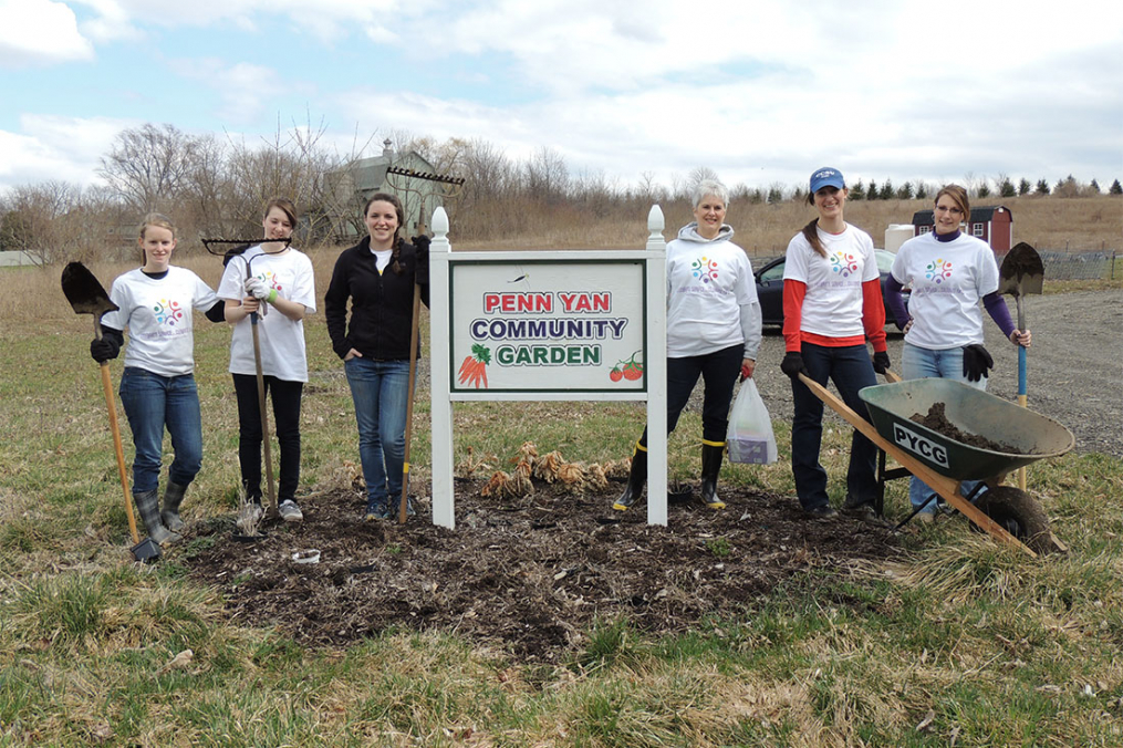 students posing by community garden sign