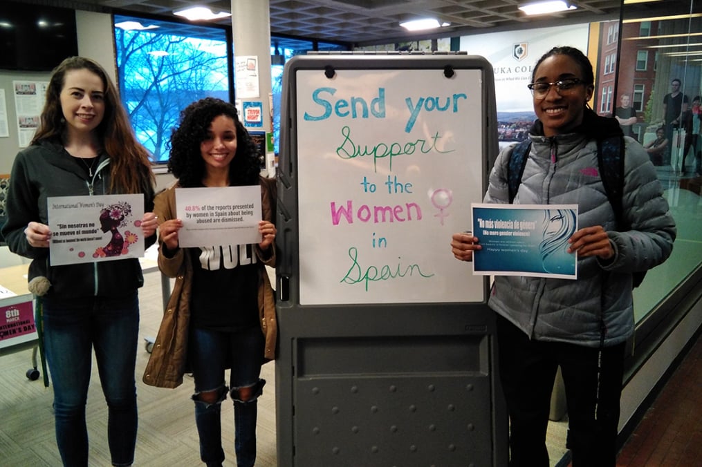 students standing by a sign saying "send your support to the women in spain"