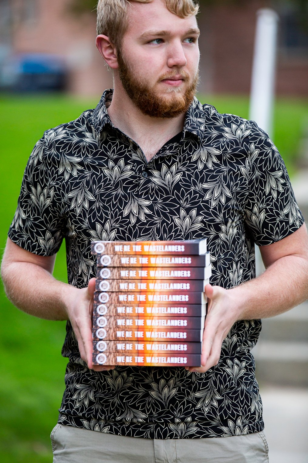 Lucas Nichols holding a stack of his recently published book 