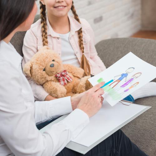 Psychologist talking to a young child and looking at her drawing